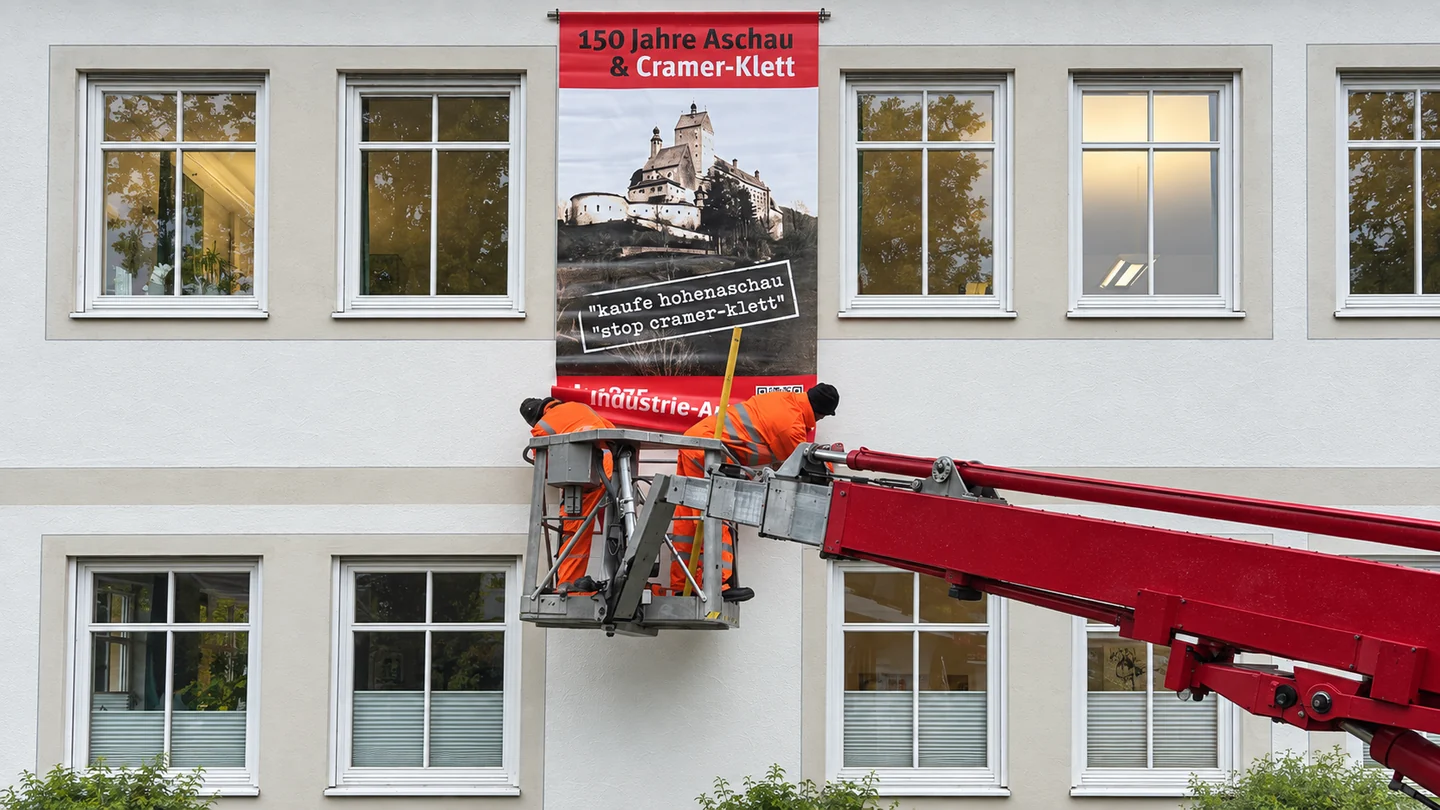 Montage eines Ausstellungsbanners an einer Hausfassade mithilfe einer Hebebühne.